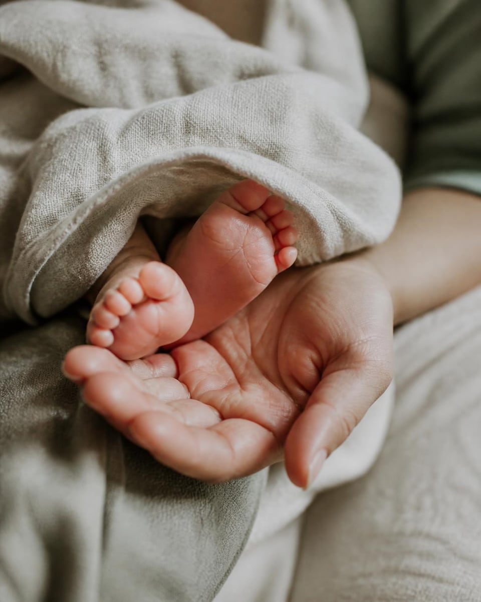 A baby’s feet resting in an open hand