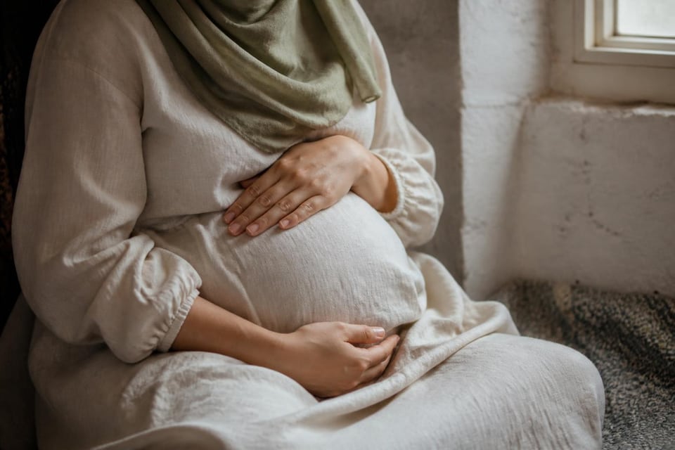 Hands resting on soft linen clothing in window light.